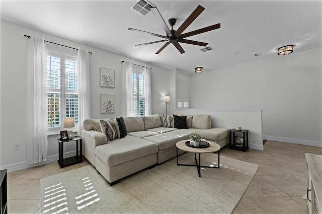 living room featuring light tile patterned flooring, ceiling fan, and a textured ceiling