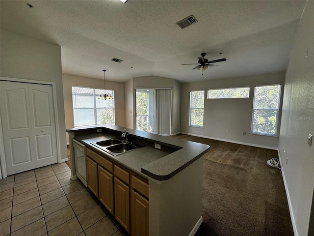 kitchen featuring a center island with sink, sink, white dishwasher, hanging light fixtures, and a textured ceiling