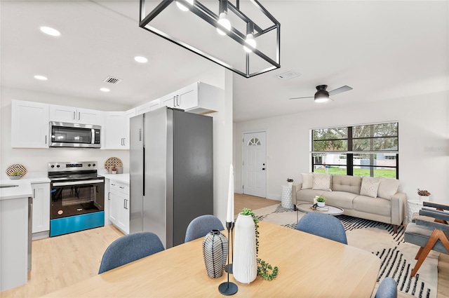 dining space featuring ceiling fan with notable chandelier and light wood-type flooring