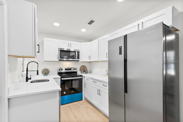 kitchen with white cabinetry, sink, stainless steel appliances, and light wood-type flooring