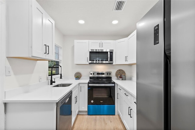 kitchen featuring white cabinets, appliances with stainless steel finishes, light hardwood / wood-style flooring, and sink