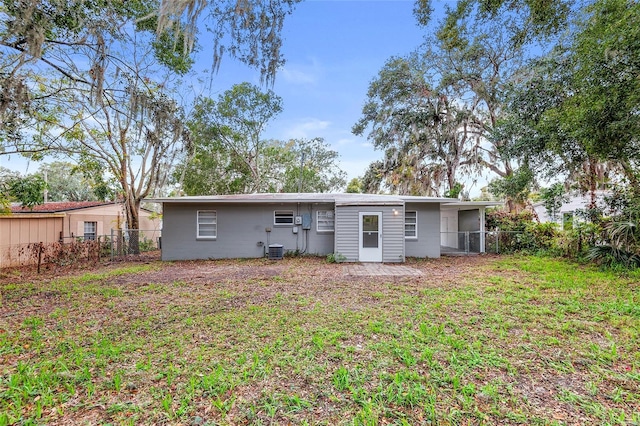 back of property featuring central air condition unit and a yard