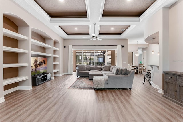 living room featuring ceiling fan, built in features, coffered ceiling, and ornamental molding