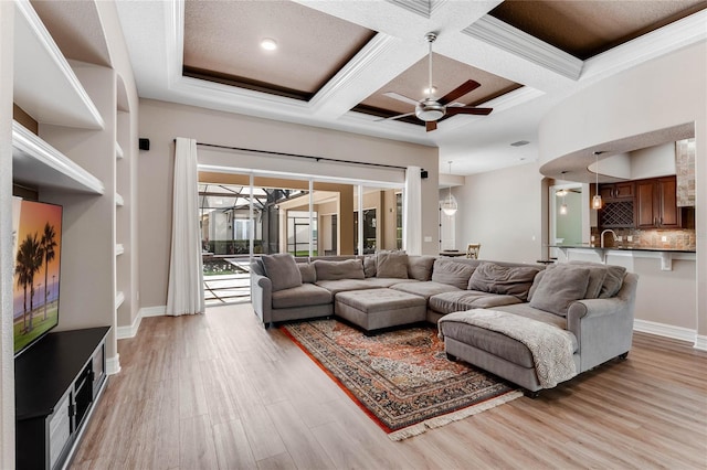 living room featuring ornamental molding, coffered ceiling, ceiling fan, beamed ceiling, and light hardwood / wood-style floors