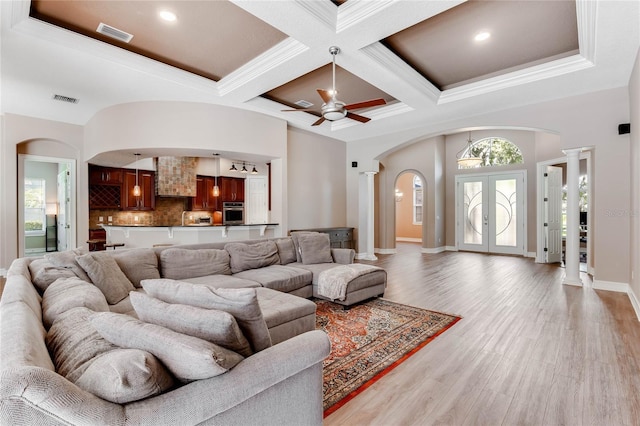 living room with ceiling fan, french doors, coffered ceiling, crown molding, and light wood-type flooring