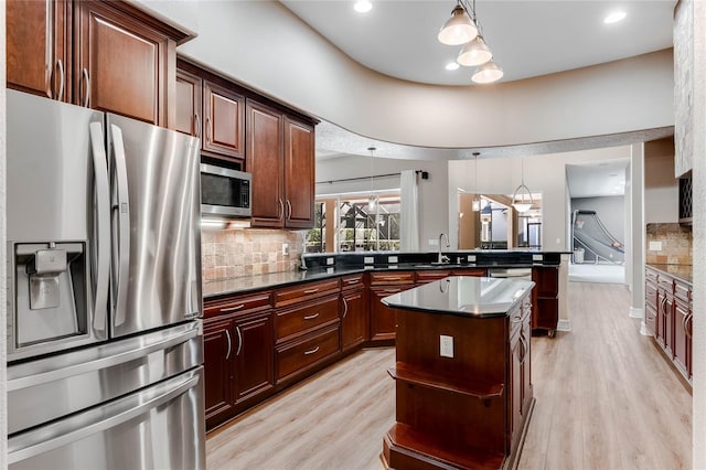 kitchen featuring sink, light hardwood / wood-style flooring, decorative light fixtures, and appliances with stainless steel finishes