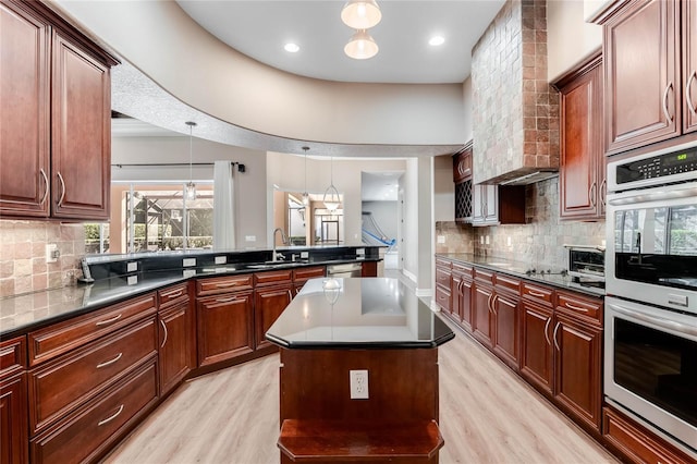 kitchen with sink, hanging light fixtures, light hardwood / wood-style floors, a kitchen island, and appliances with stainless steel finishes