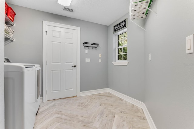 clothes washing area with washer and dryer and light parquet flooring