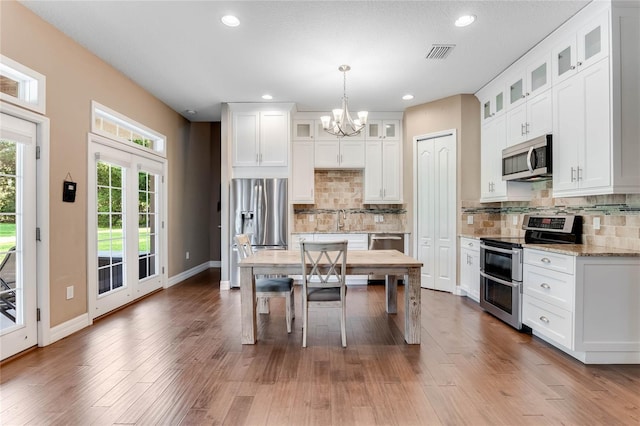 kitchen with decorative backsplash, light stone countertops, appliances with stainless steel finishes, decorative light fixtures, and white cabinetry