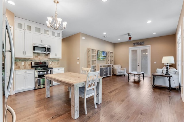 kitchen with backsplash, french doors, hanging light fixtures, white cabinetry, and stainless steel appliances