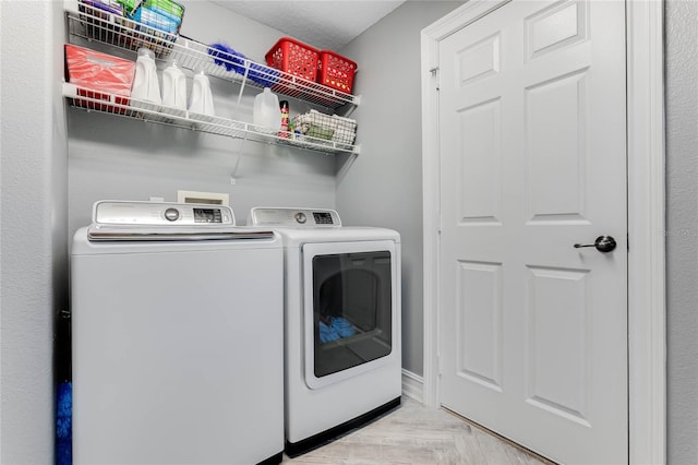 laundry room with independent washer and dryer and light parquet flooring