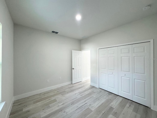 unfurnished bedroom with light hardwood / wood-style flooring and a closet