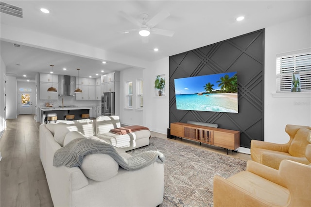 living room featuring light wood-type flooring, plenty of natural light, and ceiling fan