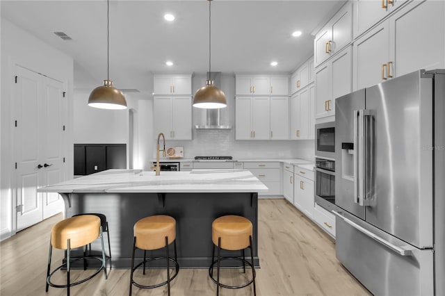 kitchen featuring a center island with sink, decorative light fixtures, and appliances with stainless steel finishes