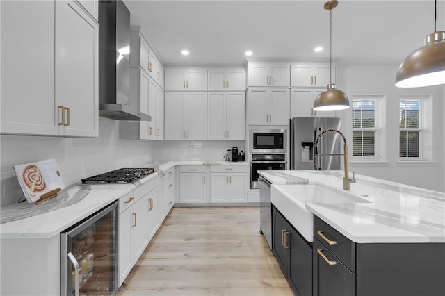 kitchen with white cabinetry, beverage cooler, hanging light fixtures, and wall chimney range hood