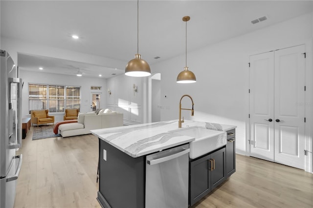 kitchen featuring stainless steel appliances, sink, a center island with sink, light hardwood / wood-style flooring, and hanging light fixtures