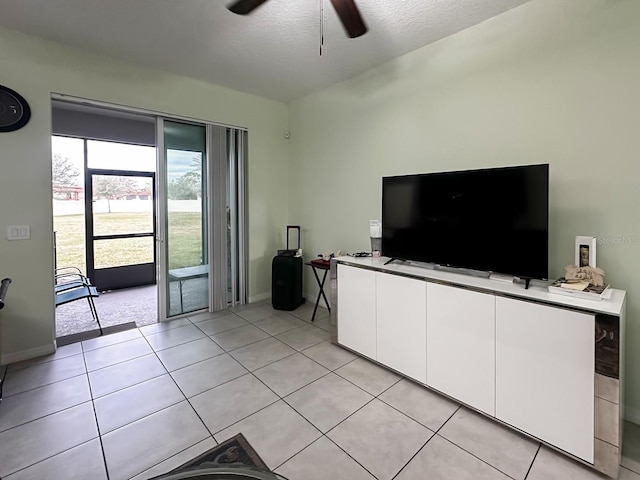 unfurnished living room with ceiling fan, a textured ceiling, and light tile patterned floors