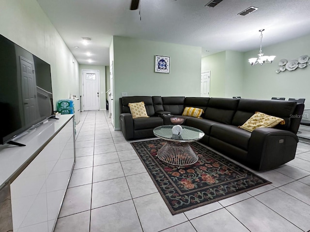 tiled living room with ceiling fan with notable chandelier and a textured ceiling