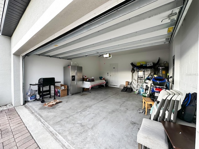 garage with stainless steel refrigerator with ice dispenser and a garage door opener