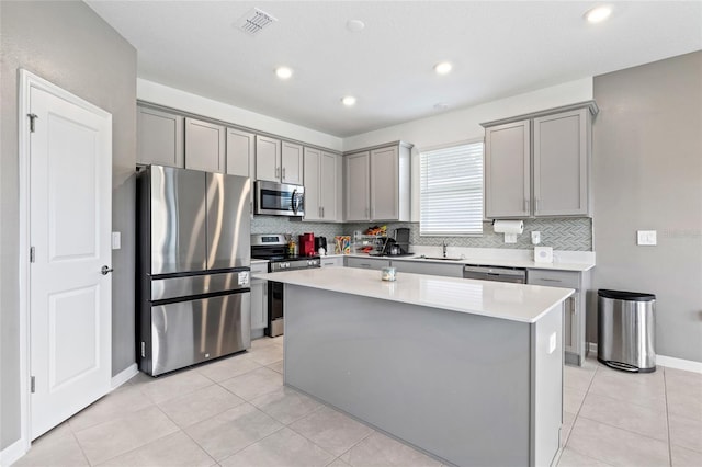 kitchen featuring a kitchen island, sink, gray cabinetry, stainless steel appliances, and light tile patterned floors