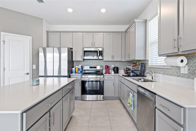 kitchen with light tile patterned floors, appliances with stainless steel finishes, sink, and gray cabinets