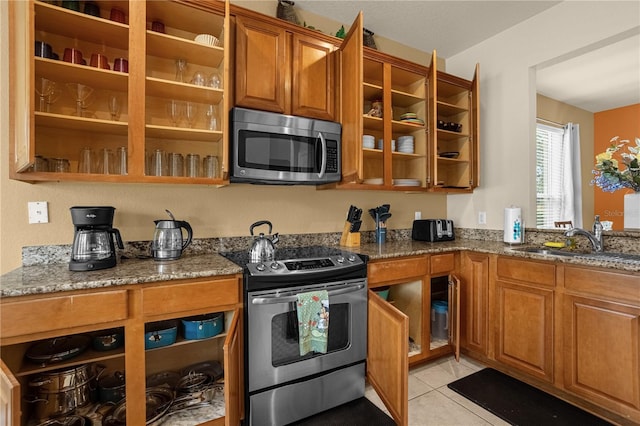 kitchen featuring dark stone counters, sink, light tile patterned flooring, and stainless steel appliances