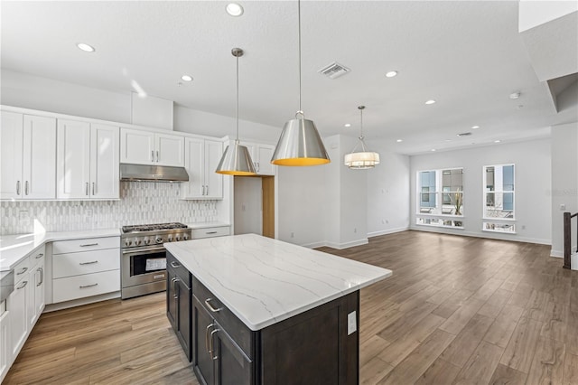 kitchen featuring high end stainless steel range, pendant lighting, a kitchen island, white cabinetry, and backsplash