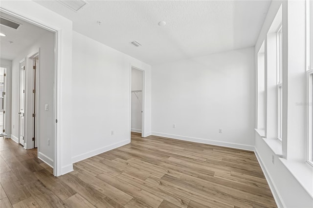 empty room featuring light wood-type flooring and a healthy amount of sunlight