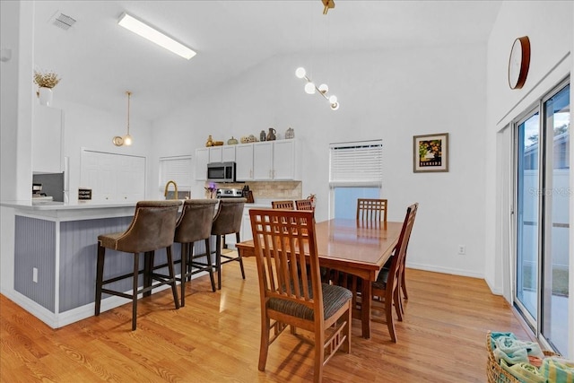 dining room featuring high vaulted ceiling, sink, and light hardwood / wood-style floors