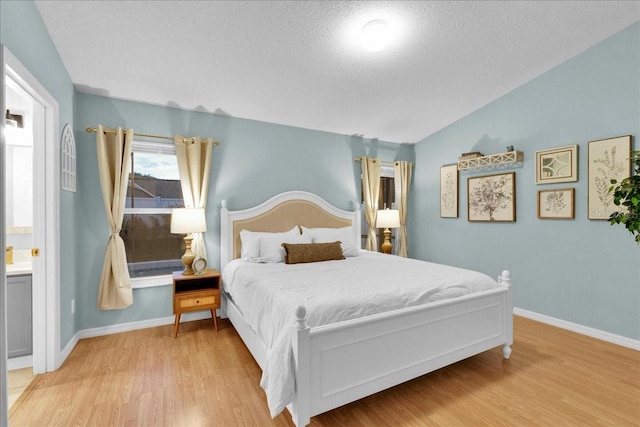 bedroom featuring connected bathroom, a textured ceiling, and light wood-type flooring