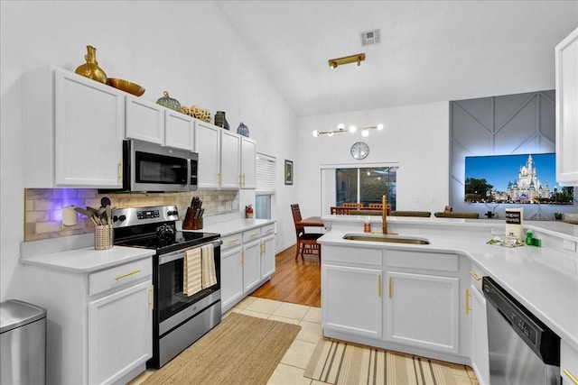 kitchen with decorative light fixtures, tasteful backsplash, sink, white cabinets, and stainless steel appliances