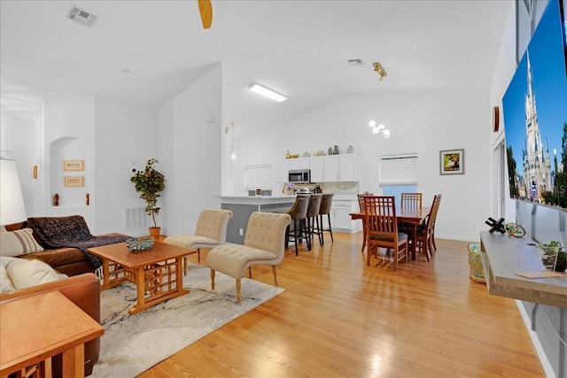 living room featuring high vaulted ceiling and light hardwood / wood-style floors