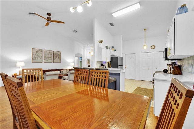 dining area with ceiling fan, light wood-type flooring, and high vaulted ceiling