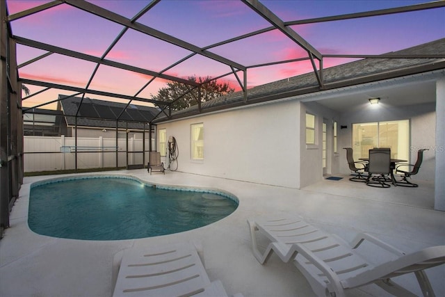 pool at dusk featuring a lanai and a patio area