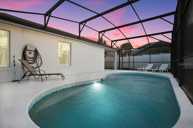 pool at dusk with a lanai and a patio area