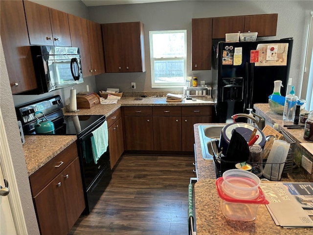 kitchen with light stone countertops, sink, dark hardwood / wood-style floors, and black appliances