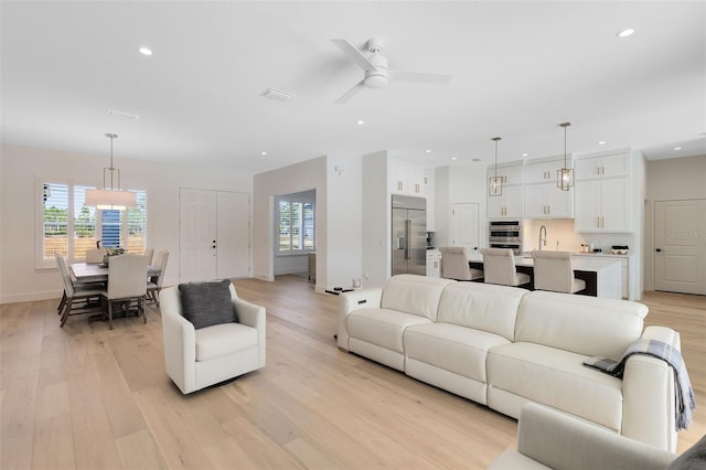 living room with light hardwood / wood-style floors, ceiling fan, and a healthy amount of sunlight