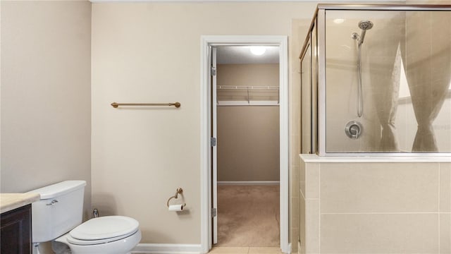 bathroom featuring a shower with door, vanity, and toilet