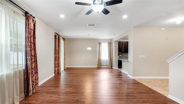 unfurnished living room with dark wood-type flooring and ceiling fan