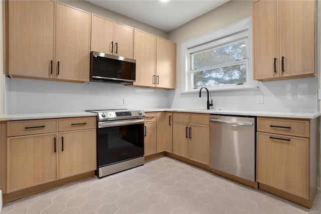 kitchen featuring sink, light tile patterned flooring, light brown cabinets, and appliances with stainless steel finishes