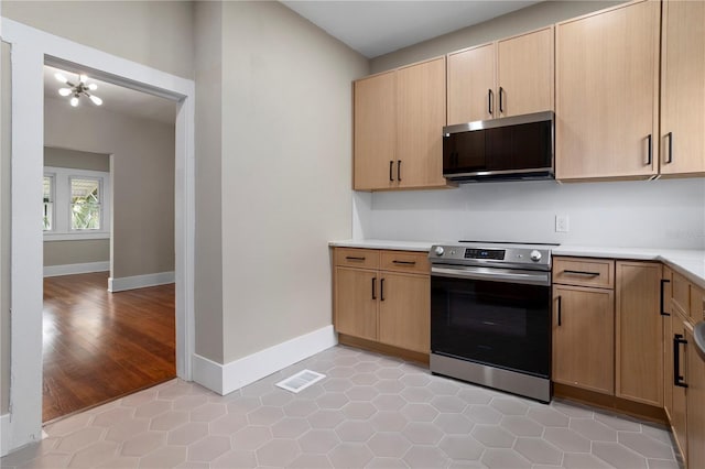 kitchen with stainless steel range with electric stovetop, light tile patterned floors, and light brown cabinets