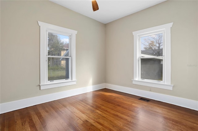 empty room with ceiling fan, a healthy amount of sunlight, and wood-type flooring