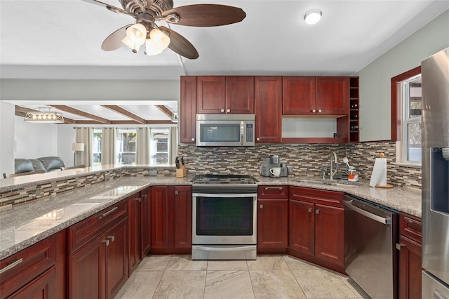 kitchen featuring appliances with stainless steel finishes, backsplash, sink, light stone counters, and beamed ceiling