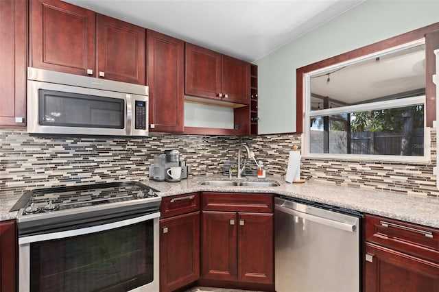 kitchen with decorative backsplash, sink, stainless steel appliances, and light stone countertops