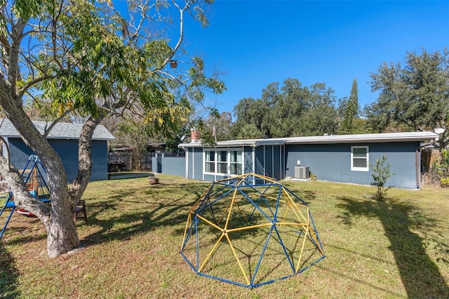 rear view of property with cooling unit and a lawn