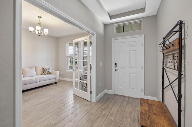 foyer entrance with a chandelier, a tray ceiling, and light hardwood / wood-style flooring