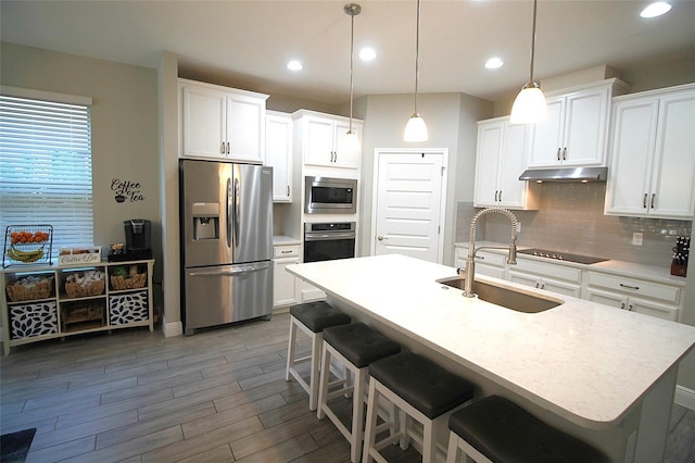 kitchen featuring tasteful backsplash, stainless steel appliances, sink, pendant lighting, and white cabinets