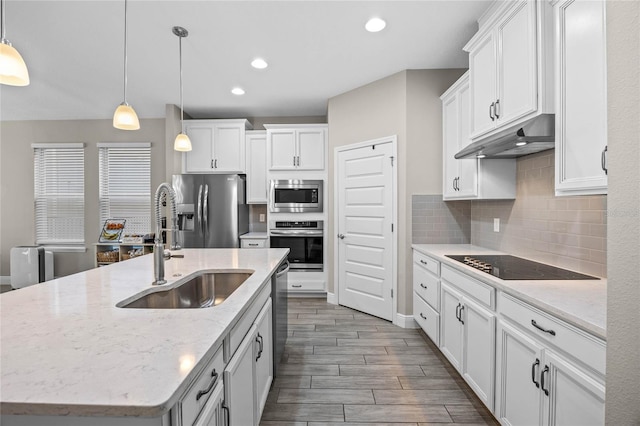 kitchen featuring appliances with stainless steel finishes, white cabinetry, a kitchen island with sink, and sink