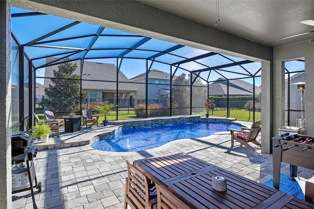 view of pool featuring pool water feature, ceiling fan, glass enclosure, grilling area, and a patio