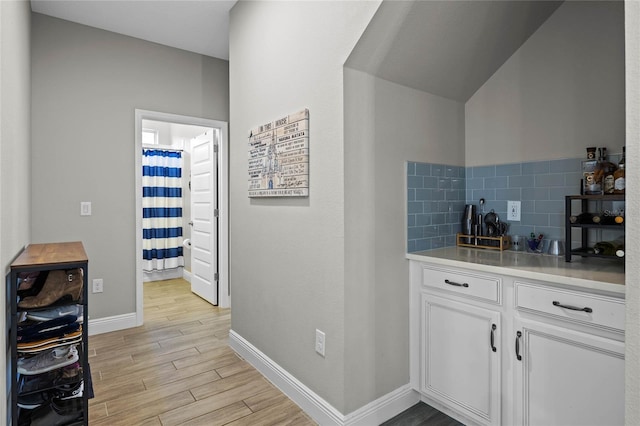 bar featuring backsplash and white cabinetry